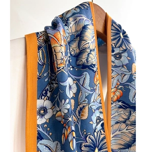 Floral cotton-linen feel skinny scarf with orange border hanging on wooden hanger