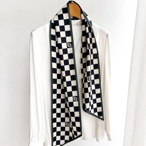 Classic black and white checkered silk scarf with green edges styled on a white shirt