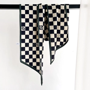 Classic black and white checkered silk scarf with dark green piping on a metal stand