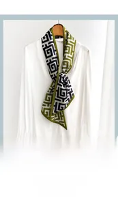 Détail d'un foulard en soie à motif géométrique noué sur une chemise blanche