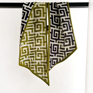 Long foulard en soie à motif labyrinthe géométrique vert olive et noir exposé