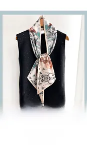 Détail d'un foulard imprimé avec motifs naturels sur un haut à paillettes noires et cintre