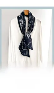 Dettaglio di un foulard in seta blu navy con motivi a catena su una camicia bianca