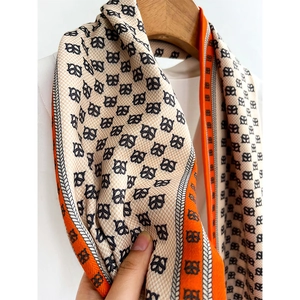 Élégante écharpe en soie beige avec motifs monogrammes noirs et bordure orange contrastée