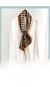 Detail view of a houndstooth and paisley silk neck scarf tied on a white shirt collar