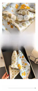 Macro detail of soft light blue silk scarf with yellow floral and geometric patterns