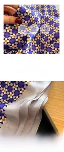 Macro detail of purple geometric silk scarf showing delicate hand-stitched edges and soft texture