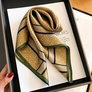 53cm square silk scarf with green border and golden geometric pattern on a magazine