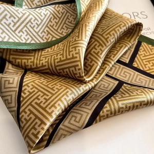 Luxurious silk scarf with green and gold Greek fret patterns and elegant drapes