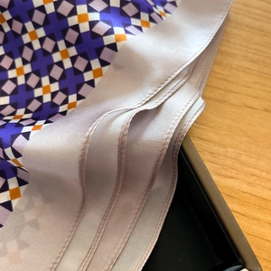Close-up of silk square scarf featuring geometric patterns and satin rolled edges