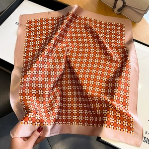 Detail of silk square scarf featuring orange geometric patterns and pink satin piping edges