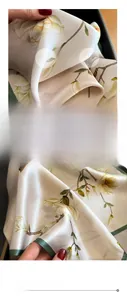 Détail d'un foulard en soie avec motif magnolia et finition de bord cousu vert foncé