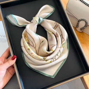Élégant foulard en soie aux fleurs de magnolia dans un coffret près d'un sac à main
