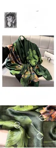Detail eines eleganten dunkelgrünen Seidenschals mit orangefarbenem Lotustextur und Glanz
