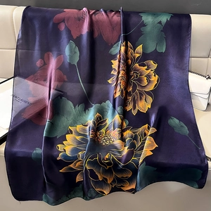 Detailstruktur eines Seidenschals mit lila Blumendruck auf einem weißen Sofa