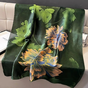 Eleganter smaragdgrüner Seidenschal mit Lotus-Print auf Ledersofa mit schicken Accessoires