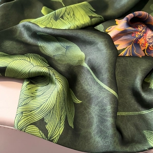 Detailansicht eines bedruckten Seidenschals mit orangefarbenen Blüten und Blattmustern