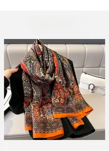 Detail view of a long paisley silk scarf with vibrant orange edges and vintage floral pattern