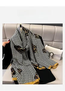 Close-up of elegant scarf featuring houndstooth pattern and golden rose floral details