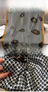 Detail of houndstooth scarf featuring golden rose embroidery and smooth silk texture