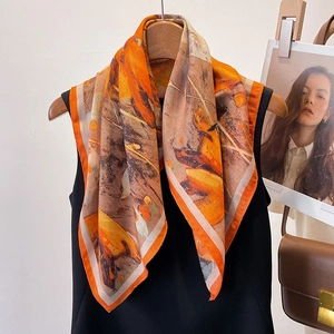 Artistic printed square scarf with abstract orange and brown patterns on a wooden hanger