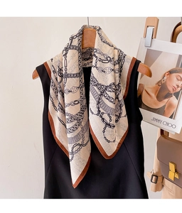 Detail of elegant chain print silk scarf draped on a wooden hanger with fashion magazine