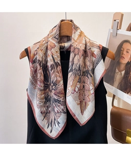 Close-up of silk square scarf featuring bohemian feather and floral print in earth tones