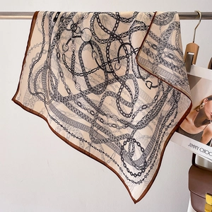 Beige chain print square silk scarf with brown borders shown in aesthetic display