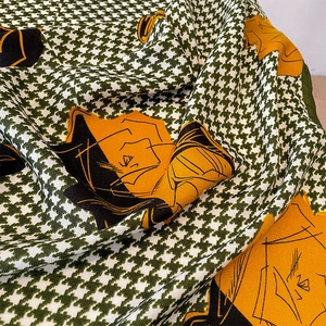 Close-up of green houndstooth scarf with orange floral print showing fine fabric texture