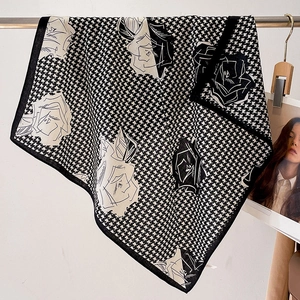 Close-up of lightweight houndstooth and floral scarf draped on a display rod