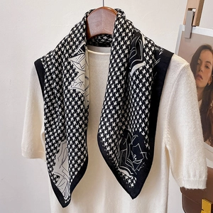 Houndstooth silk scarf with white rose floral patterns draped on a white sweater