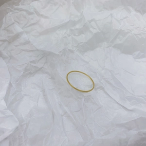 Macro shot of minimalist slim gold ring band over white textured paper background