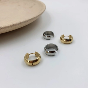 Detailed close-up of polished gold and silver hoop earrings in a minimalist style