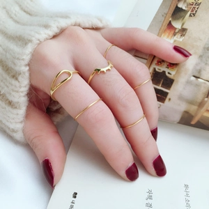 Close-up of minimalist gold stacking rings on hand with knit sweater and magazine background
