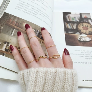 Minimalist gold ring set featuring six diverse styles worn over an open book