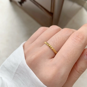 Detailed macro shot of a gold-plated pyramid stud ring with geometric industrial texture