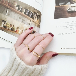 Close-up of a 5-piece minimalist gold thin ring set styled with a cozy knit sweater