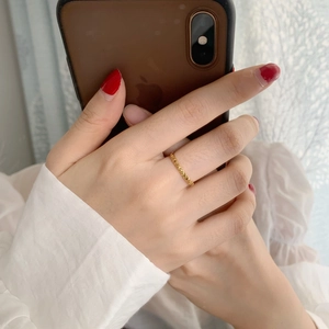 Detail of a gold plated geometric ring featuring a textured spike pattern worn on finger