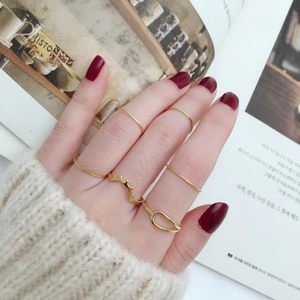 Detailed close-up of golden minimalist ring set styled with cozy knitwear background