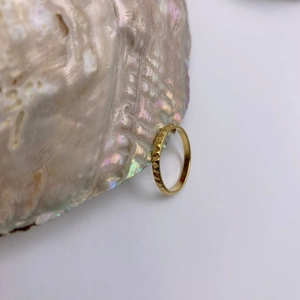 Minimalist gold geometric pyramid rivet ring displayed on an iridescent shell prop