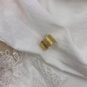 Macro shot of 18K gold plated wide ring with elegant diagonal textured ridges