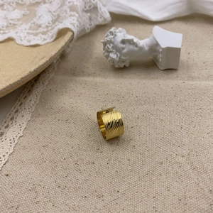 Macro view of wide gold-plated ring with hammer texture and vintage wavy metal finish