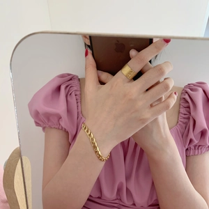 Detail of wide 18K gold plated steel ring with fine texture and chain bracelet