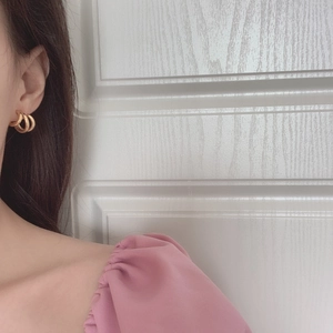 Detail of elegant gold irregular triple-hoop earrings worn by a model in a natural setting