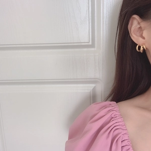 Detailed view of gold triple hoop earrings worn by a model in a minimalist style