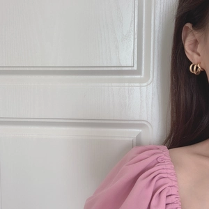 Close-up of minimalist triple-layered gold hoop earrings worn by a model in a soft scene