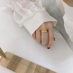 Detail of a layered golden ring featuring irregular multi-layered texture and metallic luster