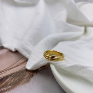 Minimalist gold textured ring with triple-layer groove design on white fabric