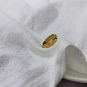 Detailed view of polished gold triple band stacked ring on minimalist linen texture