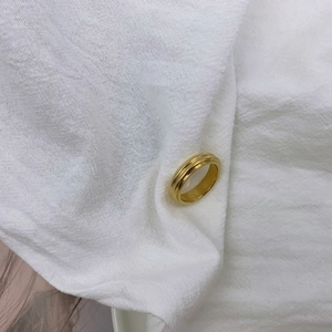 Minimalist gold textured ring with dual parallel grooves on white fabric background